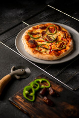 pizza con vegetales sobre parrilla fondo negro y cortador de pizza