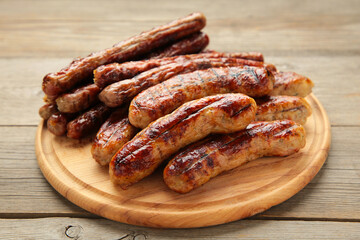 Grilled sausages on wooden board on grey background