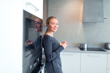 beautiful smiley woman in the kitchen with a water glass
