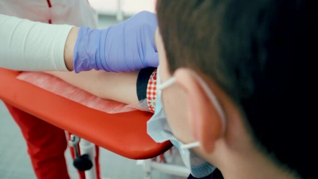 Biologist or nurse in modern clinic preparing boy patient for taking blood taste after corona virus infection. Medicines research concept and defeating dangerous covid-19 infection