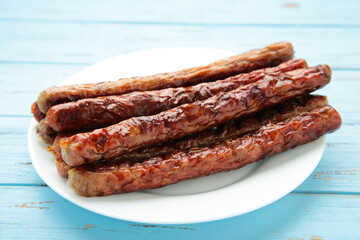 Roasted sausage on plate on blue background