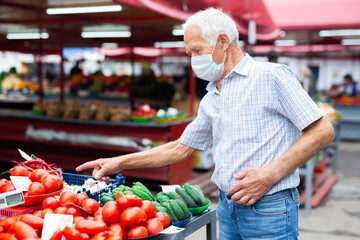 retired european man wearing medical mask protecting against virus buying tomatoes in market