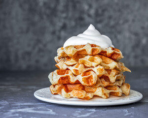 Homemade cottage cheese waffles with whipped cream lie in a slide on a white saucer
