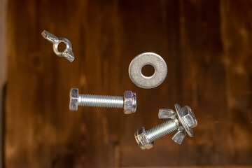 falling screws, washer and retaining nut on blurred brown background - 427245609