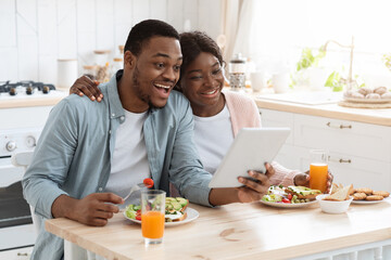 Joyful Black Millennial Couple Using Digital Tablet For Video Call In Kitchen