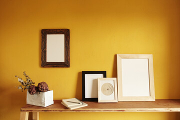 Wooden frames mockup. Composition with a flowerpot, dried artichokes, a notebook . Against the background of a yellow wall