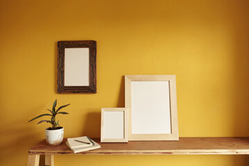Wooden frames mockup. Flowerpot on a pile of books on an old wooden shelf. Composition on a yellow wall background
