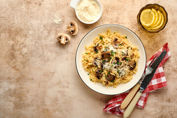 Dining italian pasta risoni, mushrooms, sauce, Parmesan, thyme, garlic, olive oil, in white plate over slate, stone or concrete background. Top view with copy space. Italian cuisine.