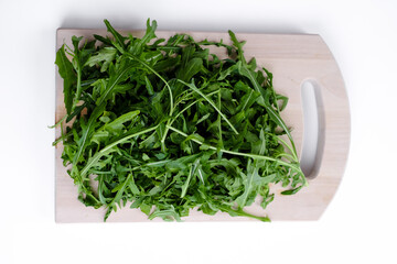 Fresh arugula  leaves at white wooden board . Concept of green healthy salad. Top view