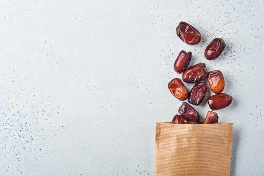 Dried sliced date fruit in paper bag on white background with copy space. Snack vegan sugarfree food.