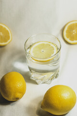 Glass of water with a lemon slice. Lemon cut in half in studio on isolated white background.