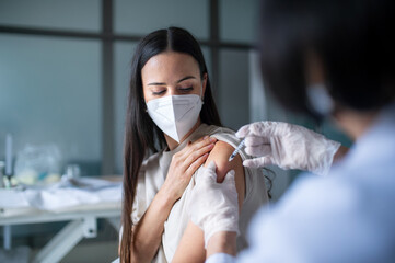 Woman with face mask getting vaccinated in hospital, coronavirus and vaccination concept.