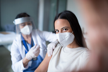 Woman with face mask getting vaccinated and taking selfie in hospital, coronavirus and vaccination concept.