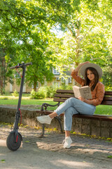 A young girl is sitting on a park bench with the book in her hands