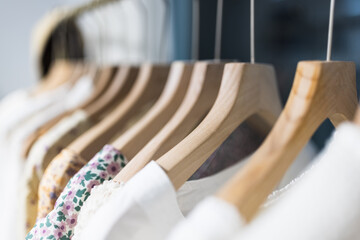 Row of different female clothes hanging on rack in hipster fashion show room in shopping mall. Trendy women wear
