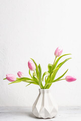 Bouquet of gentle pink tulips in ceramic vase on white background