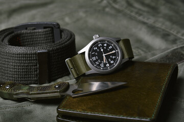 Vintage military watch with nato strap and tactical knife on army green background, Classic timepiece mechanical wristwatch, Military men fashion and accessories.