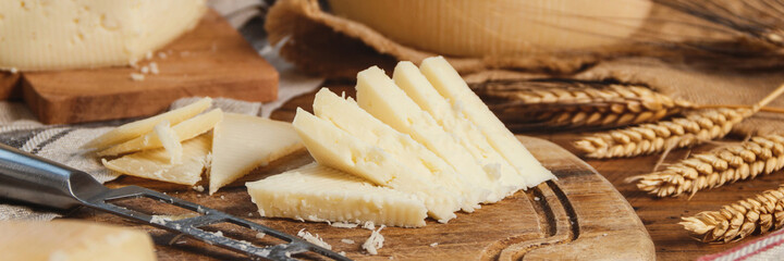 Fototapeta Pieces of  fresh homemade cheese on a wooden board with a knife close up obraz
