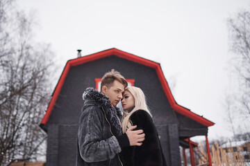 Obraz premium man and woman sitting on the porch of a house. young happy couple in love outdoors in the winter