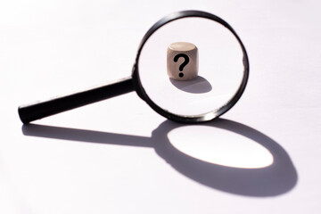 Black Magnifying glass and a question mark on a wooden cube . FAQ frequency asked questions, Answer...