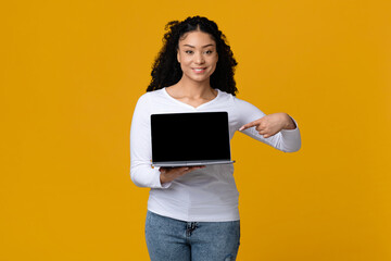 Smiling African Woman Pointing At Laptop With Black Screen In Her Hands