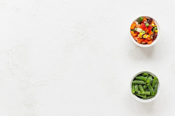Mix of frozen vegetables in white bowls. Horizontal orientation, copy space, top view.