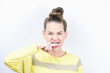 Young girl bites his teeth with braces finger on white background. Concept of dentistry and installation of braces.