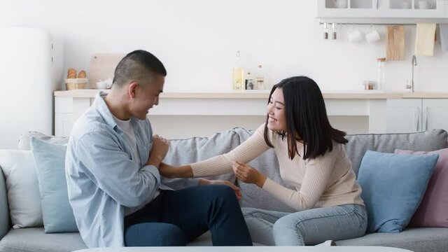 Happy Asian Couple Tickling Each Other Having Fun At Home