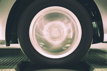 Close up of vehicle tire and rim rotation with blurry motion on roller Chassis dynamo