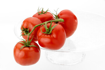 tomatoes isolated on clear glass raised plate isolated on white background. copy space