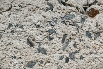 Gray old concrete surface with cracks and stones as a background texture.