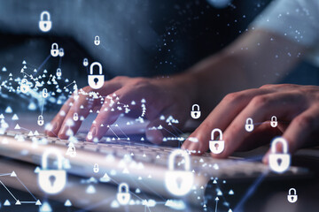 A programmer is typing a code on a keyboard to protect a cyber security from hacker attacks and save clients confidential data. Padlock Hologram icons over the typing hands.