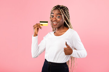 Excited black woman holding credit card showing thumbs up
