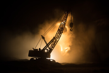 Abstract Industrial background with construction crane silhouette over amazing night sky with fog and backlight. Tower crane against the foggy sky at night.