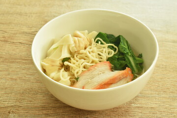 Chinese egg yellow noodles with barbecue pork and dumpling in clear soup on bowl