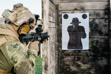 Soldier in the uniform (Cropat woodland pattern) taking aim at the target on the shooting range...
