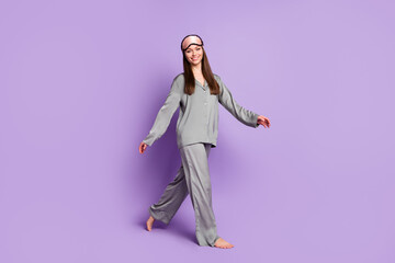 Full length body size photo of girl in grey sleep wear mask walking forward smiling isolated pastel...