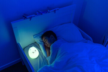 boy sleeping with led night lamp, soft focus