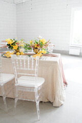 serving on a lemon-colored table. Transparent chairs, rectangular table in a white hall