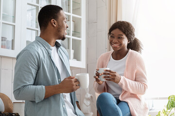 Coffee Time. Portrait Of Cheerful Black Couple Enjoying Hot Drinks In Kitchen