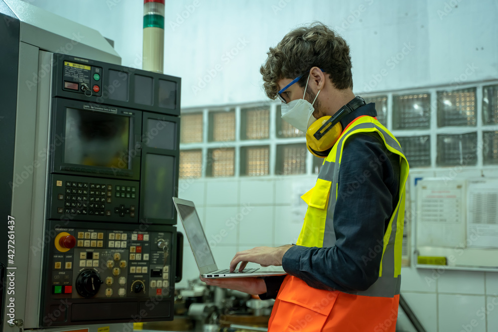 Poster professional technicians wears face mask standing and holding laptop with confident working at facto