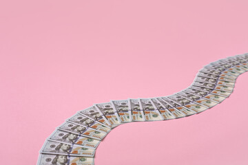 Money path made of 100 dollar bills on pink background with copy space.