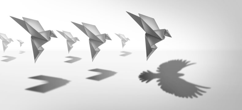 Ambitious leadership and leader vision or leading ambition as a business symbol for innovative imagination and success metaphor as an origami paper bird casting a shadow of powerful real wings