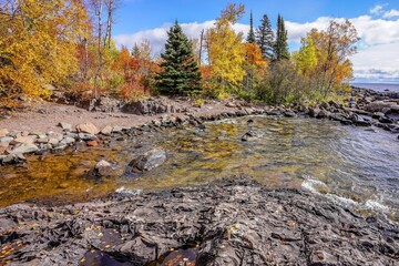 Colorful Autumn trees along a cove on a rocky beach on Lake Superior at Tettegouche State Park
