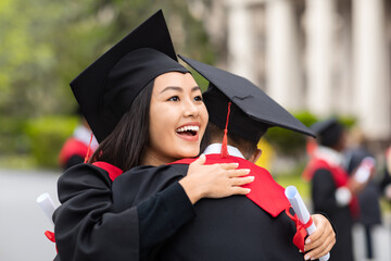 Cheerful asian lady hugging her boyfriend while graduation ceremony