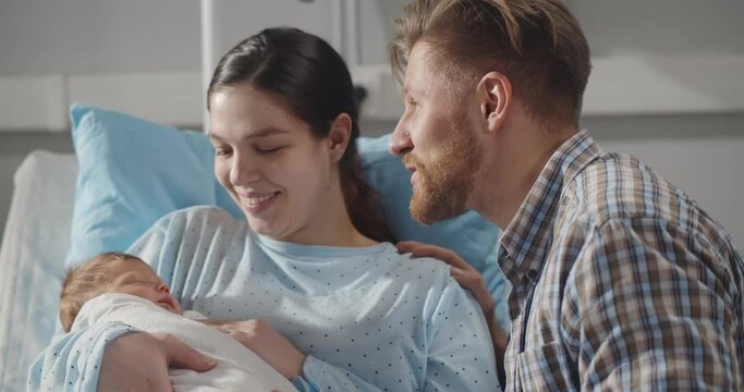 Portrait of happy young family with cute baby at hospital