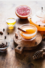 Grapefruit tea with spices and honey in a glass cup and teapot.