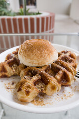 A baked croissant dough in waffle iron with a scoop of vanilla ice cream.