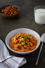 Thick pumpkin soup with baked chickpeas and radish sprouts in a plate with a glass of milk on the table, delicious healthy dinner
