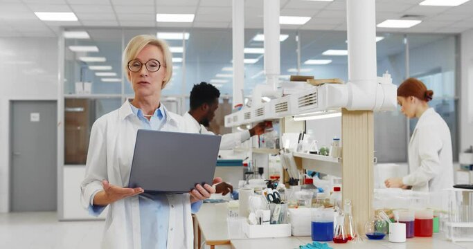 Portrait of female researcher laptop talking on camera about research in chemistry lab